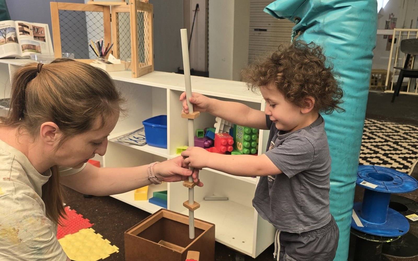An educator building a wooden tower with a toddler during an educational childminding session