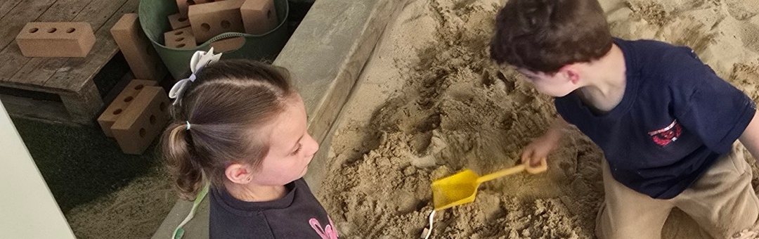 Two children digging in the sandpit at The Learning Nest Co.